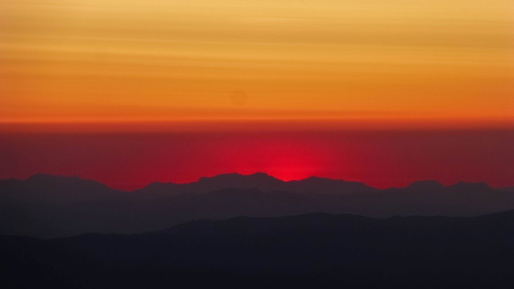 Sunrise. A red glow behind the mountains in the far distance